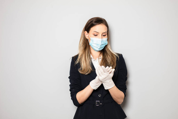 young elegant business woman wearing facial protection mask and fixing her gloves, this is the outbreak outfit work - Photo, image