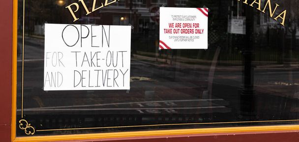 Pizza restaurant window has open for take out and delivery signs in the window because of the Coronavirus COVID-19 pandemic shutdown. - Photo, Image