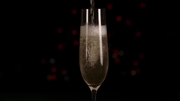 Nalévání šampaňského nebo šumivého vína do skla na barevné blikající bokeh, černé pozadí. Vytékají bubliny a nahoře bílá pěna. Zavřít - Záběry, video
