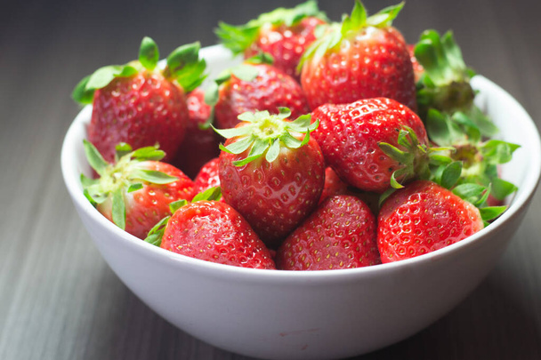 Photo session of fresh organic strawberries. It also includes gray wood textures and a white bowl. The combination of bright colors stands out. - Valokuva, kuva