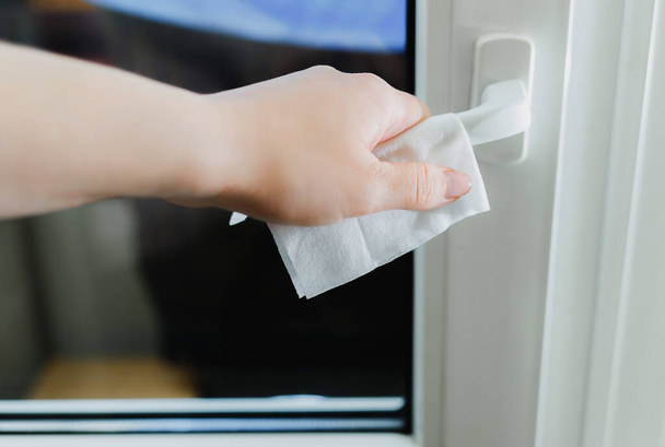 Een close-up van de hand van een man houdt een deurkruk door een servet. Bescherming tegen contact met oppervlakken op openbare plaatsen tijdens de Kovid-19 pandemie. Quarantaineconcept - Foto, afbeelding