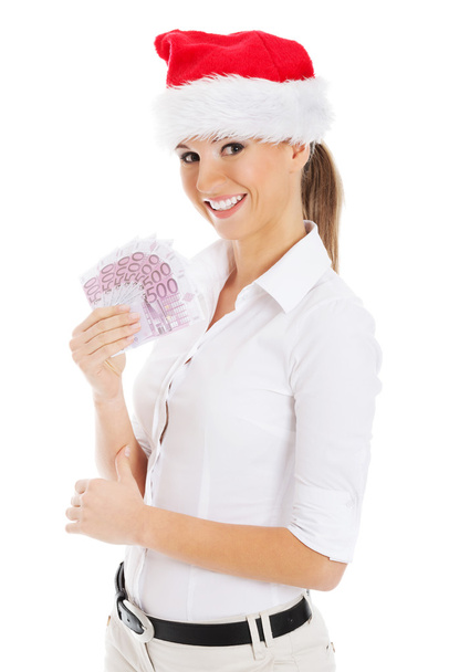 młody biznes kobieta trzyma pieniądze w santa hat. - Zdjęcie, obraz