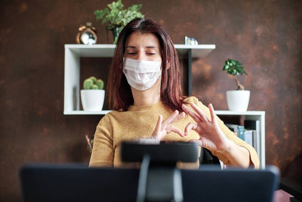 eine freiberufliche Frau mit Maske, die während der Coronavirus-Krise zu Hause arbeitet - stay home concept - Foto, Bild