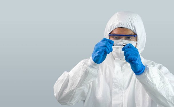 Эпидемиологические исследователи в вирусной защитной одежде изучают образцы крови пациентов, инфицированных вирусом Ковид-19. Процесс тестирования коронавирусной болезни 2019 года в лаборатории
. - Фото, изображение