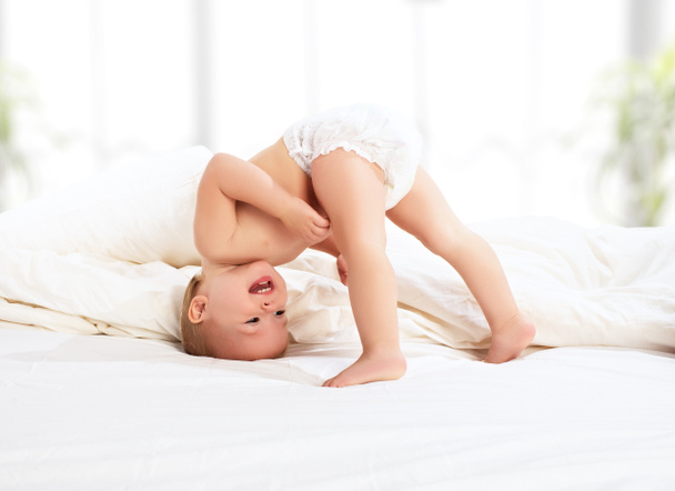 счастливый ребенок, играющий в постели
 - Фото, изображение
