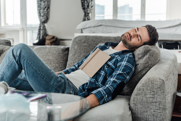 Вибірковий фокус чоловіка з книгою спить на дивані вдома
 - Фото, зображення
