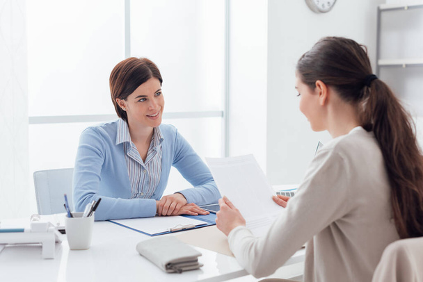 Business meeting in the office: a businesswoman is talking and checking a contract with the customer - Foto, Imagem