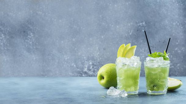 Green cocktail with ice and mint. Bar concept. Apple mojito with mint and ice on the blue background, slider format image - Fotografie, Obrázek