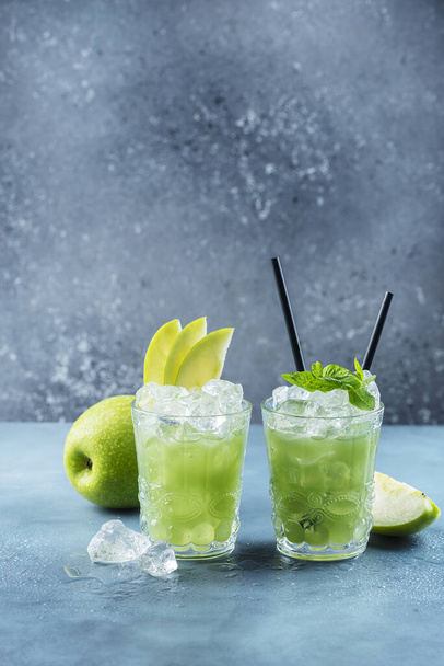 Green cocktail with ice and mint. Bar concept. Apple mojito with mint and ice on the blue background, selective focus image - 写真・画像
