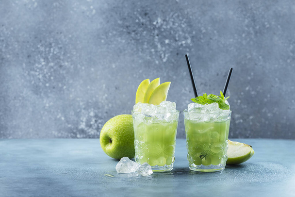 Πράσινο κοκτέιλ με πάγο και μέντα. Έννοια μπαρ. Μοτζίτο μήλου με μέντα και πάγο στο μπλε φόντο, επιλεκτική εικόνα εστίασης - Φωτογραφία, εικόνα