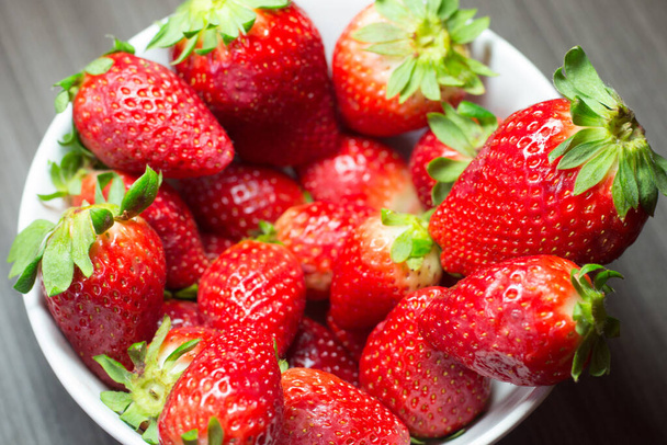 Séance photo de fraises bio fraîches. Il comprend également des textures en bois gris et un bol blanc. La combinaison de couleurs vives se distingue
. - Photo, image