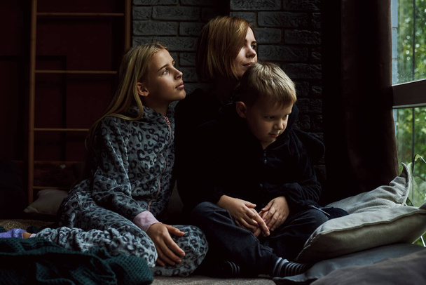 Mom with children on the bed. A woman with a boy and a girl are lying in their pajamas. Parenthood concept, relationship mom and children. - Foto, afbeelding