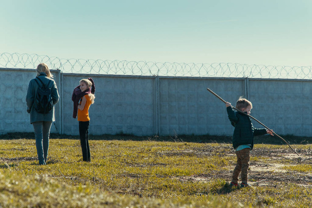Mom with two children near the fence with barbed wire. - Photo, image