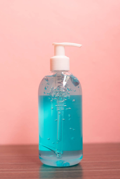 Close up blue alcohol gel on pink pastel background. - Photo, Image