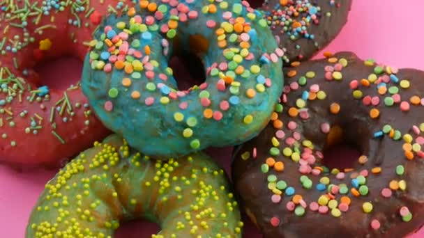 Donuts américains avec glaçure colorée et poudre. Tourner sur un fond rose vue rapprochée
 - Séquence, vidéo