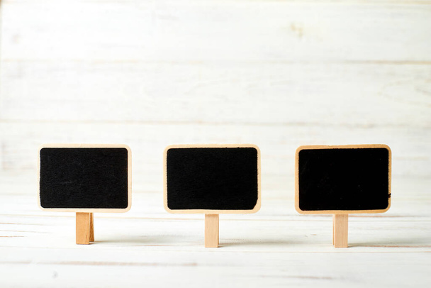 Small black posters in frames on a white wooden background. Template for inscriptions. - 写真・画像