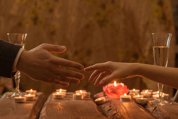 A man and a woman at a romantic dinner. The hand of a man and a woman reach for each other by candlelight. - Fotoğraf, Görsel