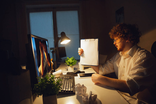 Człowiek pracujący samotnie w biurze podczas kwarantanny COVID-19, zostający do późna w nocy - Zdjęcie, obraz