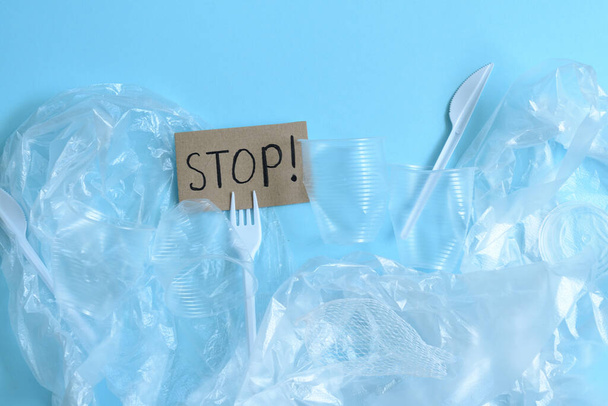 plastic bags and disposable utensils on a blue background. Text STOP.Recycling concept. ecology, environmental pollution. earth day. The concept of waste disposal and ecology. Flat lay, top view - Photo, Image