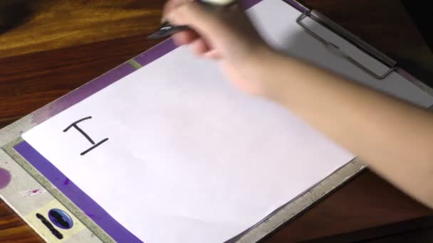 Una chica está escribiendo texto Lo siento en el papel con una pluma grande
. - Imágenes, Vídeo