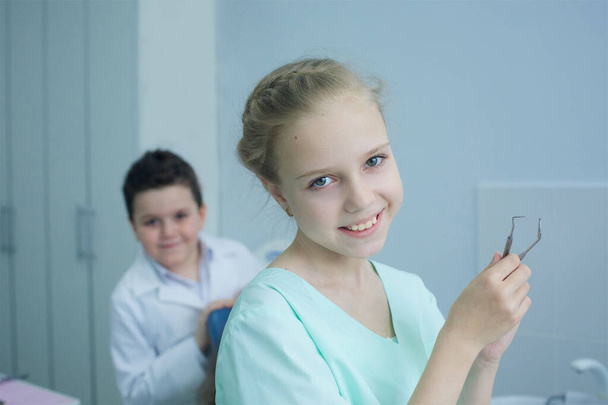 Fogorvososdit játszik a fogorvosi rendelőben. Lány orvos kezeli a beteget. - Fotó, kép