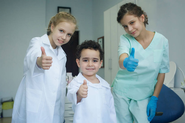 Tandarts spelen in het tandartspraktijk. Kleine dokter baby jongen en meisje assistenten. - Foto, afbeelding