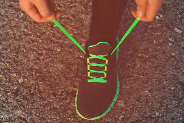 Primer plano de una mujer deportiva atando cordones en zapatos deportivos. Preparación para un maratón, estilo de vida saludable
 - Foto, Imagen