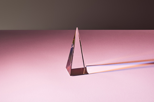 crystal transparent pyramid with light reflection on pink surface - Foto, Imagem