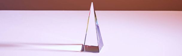 Kristall transparente Pyramide mit Lichtreflexion auf braunem Hintergrund, horizontale Ernte - Foto, Bild
