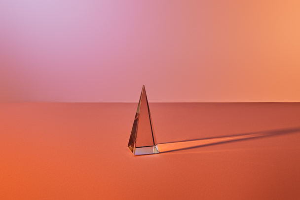 crystal transparent pyramid with light reflection on orange background - Фото, зображення