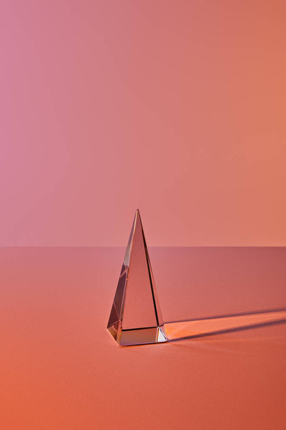 crystal transparent pyramid with light reflection on orange background - Foto, afbeelding