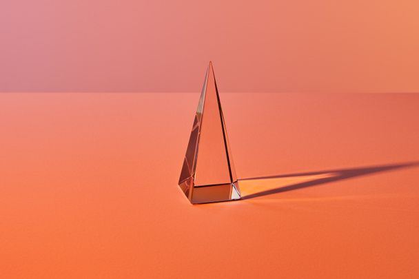 crystal transparent pyramid with light reflection on orange background - Photo, Image