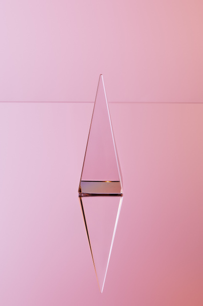 кристалічна прозора піраміда з відображенням на рожевому фоні
 - Фото, зображення