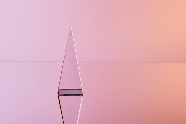 crystal transparent pyramid with reflection on pink background - Photo, Image