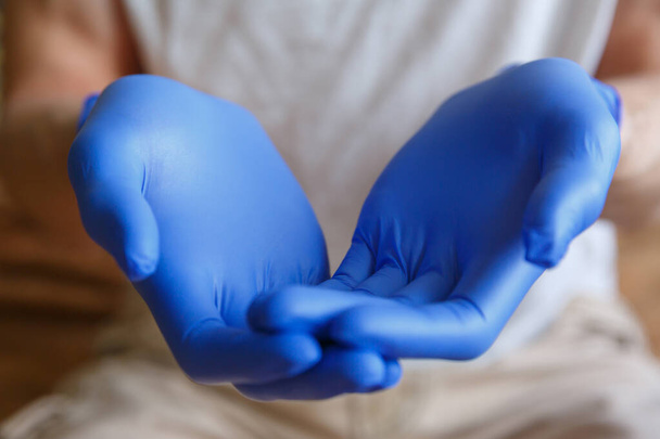 Men's hands in blue medical gloves are holding something. Hand gesture - Fotó, kép