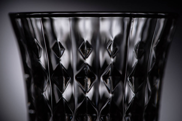 close up view of empty faceted shot glass on dark background - Foto, Bild
