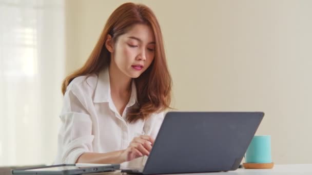 Joven adulto asiático mujer trabajo en casa oficina, cerrar ordenador portátil terminar de trabajar. Trabajo desde la vida en el hogar, la tecnología de la información, el estilo de vida doméstico o Internet concepto de trabajo remoto. Cámara portátil
 - Metraje, vídeo