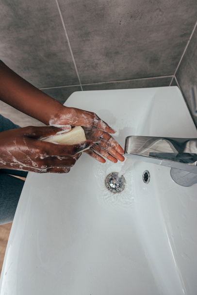 cropped view of african american girl washing hands with soap in bathroom - Zdjęcie, obraz