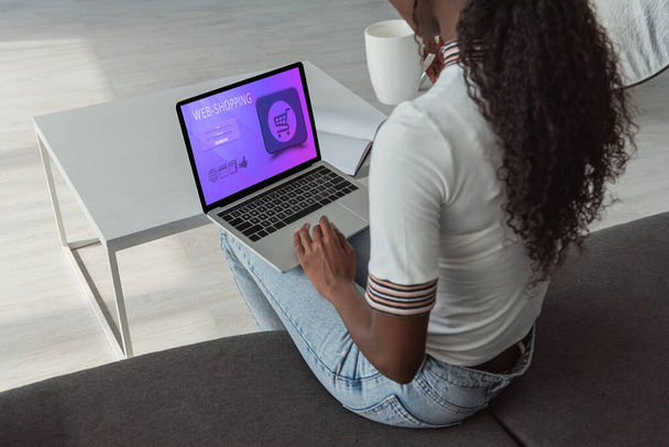 vista de ángulo alto de la chica afroamericana utilizando el ordenador portátil con el mejor sitio web de compras en la pantalla
 - Foto, Imagen