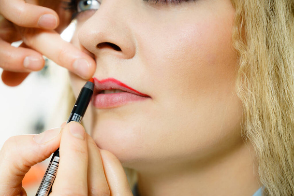 Profissional make up artista aplicando na mulher moda modelo lábios vermelho brilho labial ou batom usando escova. Visage conceito de último toque. - Foto, Imagem