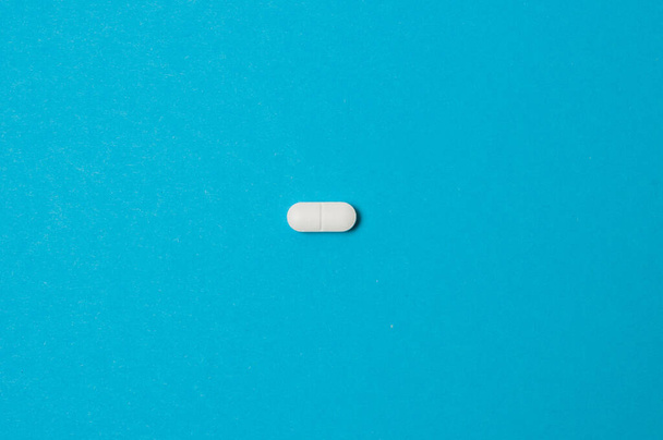 Bílá pilulka na modrém pozadí, izolovat, s místem pro text. - Fotografie, Obrázek