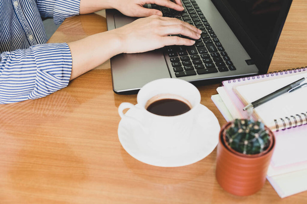 electieve focus vrouw hand droeg blauw gestreept shirt Typing op keybord, werk online lifestyle ontspannen thuis met koffie, thuis werken met laptop, werk van thuis uit - Foto, afbeelding