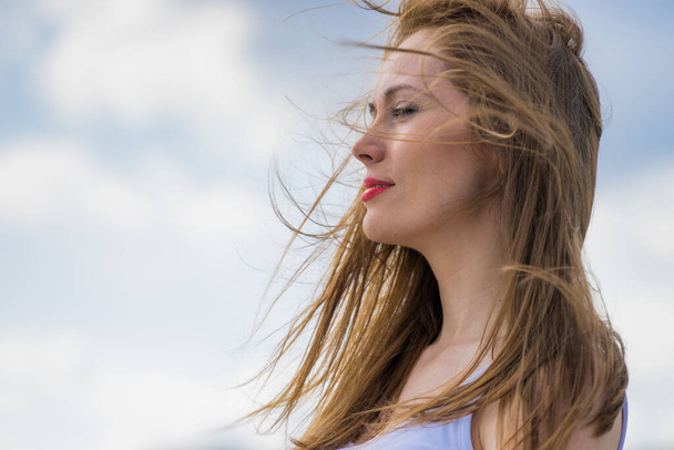 Gorgeous romantic girl outdoors. Brown long hair blowing in the wind against sky. - Foto, Imagem