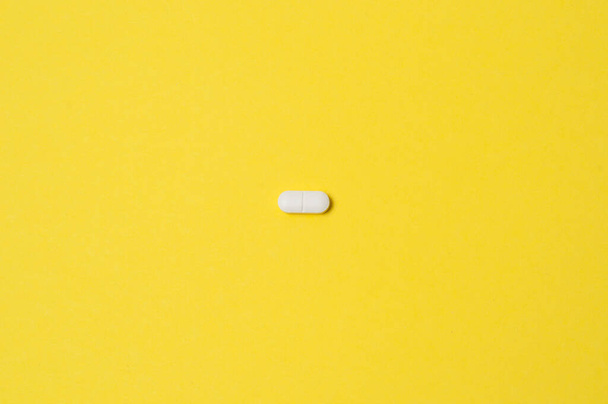 White pill on yellow background, isolate, with place for text - Photo, image