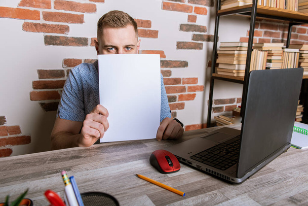 Young male businessman working remotely, holding a piece of paper and looking through it - Foto, immagini
