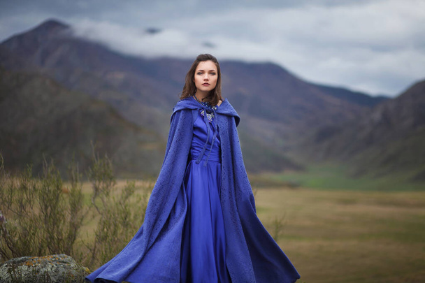 Egy gyönyörű kék ruhás lány sétál a hegyekben.. - Fotó, kép