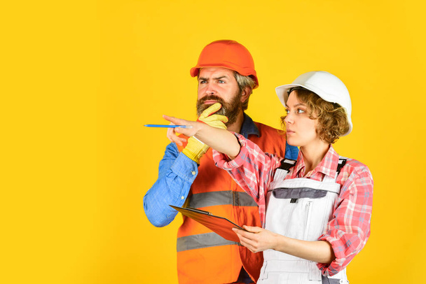 Renovation concept. Family counting finances for renovation. Couple planning changes renovation apartment. Woman and man wear safety hard hat. Redevelopment of home. Couple looking at documents - Foto, immagini