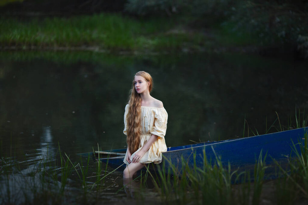 lang haar blond zittend in een gezonken boot, melancholie, depressie - Foto, afbeelding