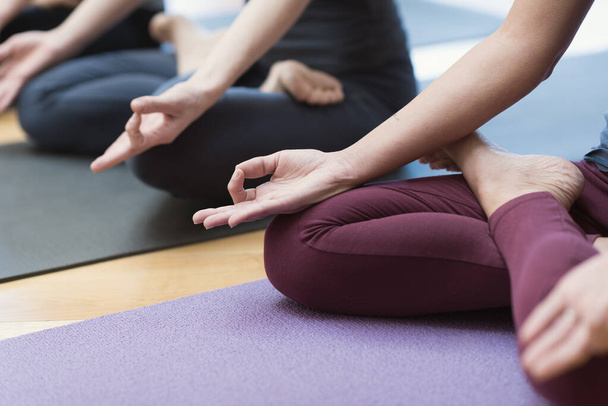 Women practicing yoga together and sitting in the lotus pose: mindfulness meditation, spirituality and healthy lifestyle concept - Valokuva, kuva