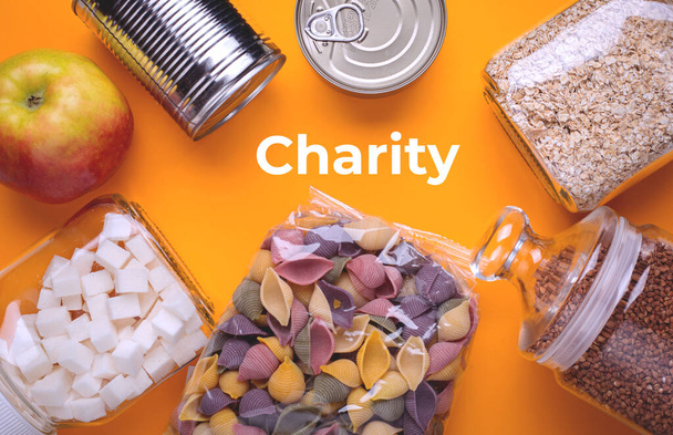 Lebensmittelspende auf gelbem Hintergrund mit der Aufschrift "Charity" - Foto, Bild